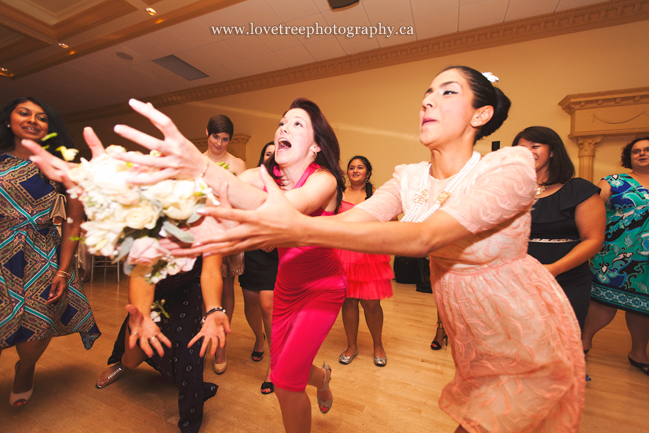Single women clamor for the bride's bouquet in a classic bouquet toss | fun and fresh wedding photography by www.lovetreephotography.ca